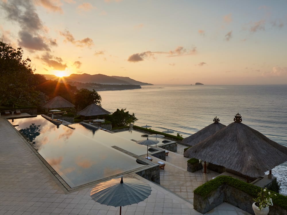 Three tiered infinity pool, looking out to sea, with the sun setting behind.