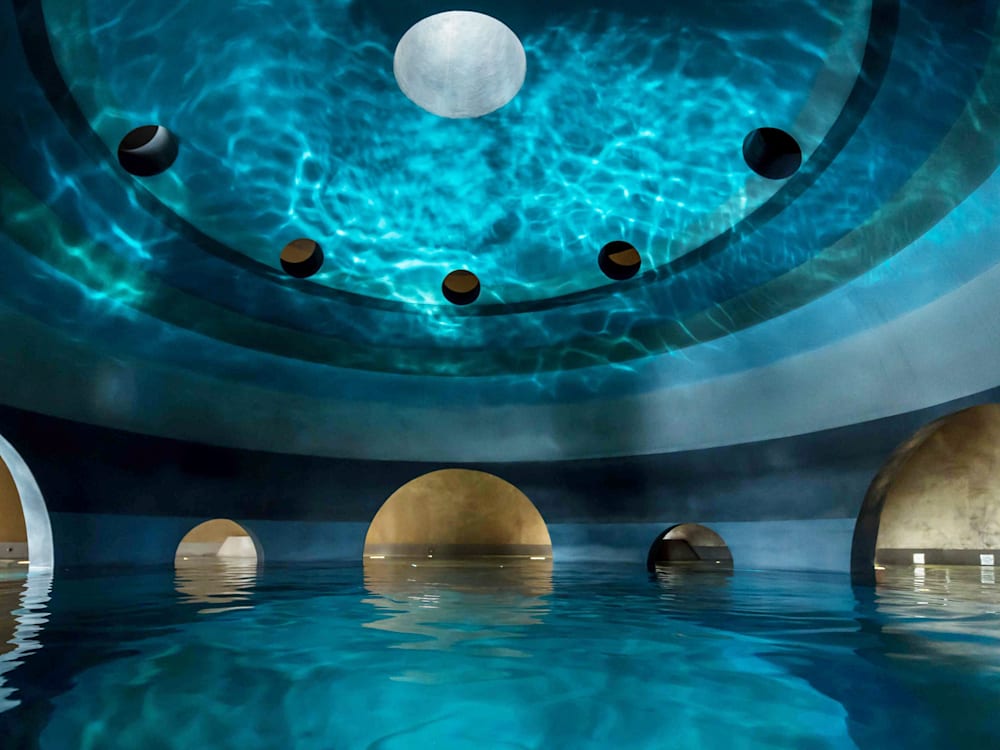 A circular spa pool, water reflects onto the domed ceiling.