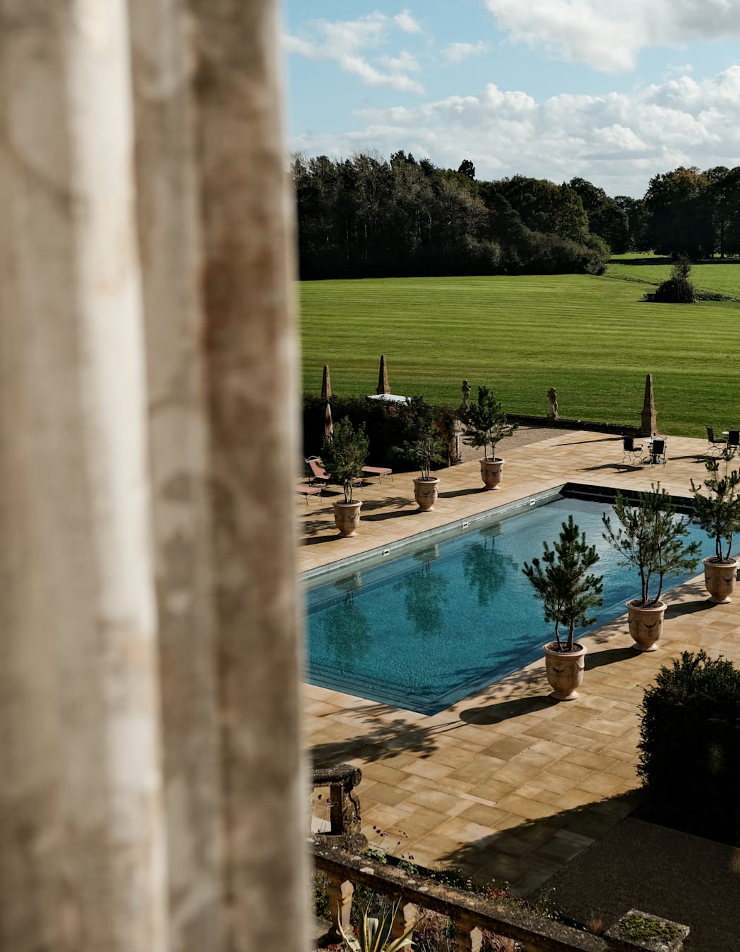 A view through a window of a large swimming pool in beautiful country estate