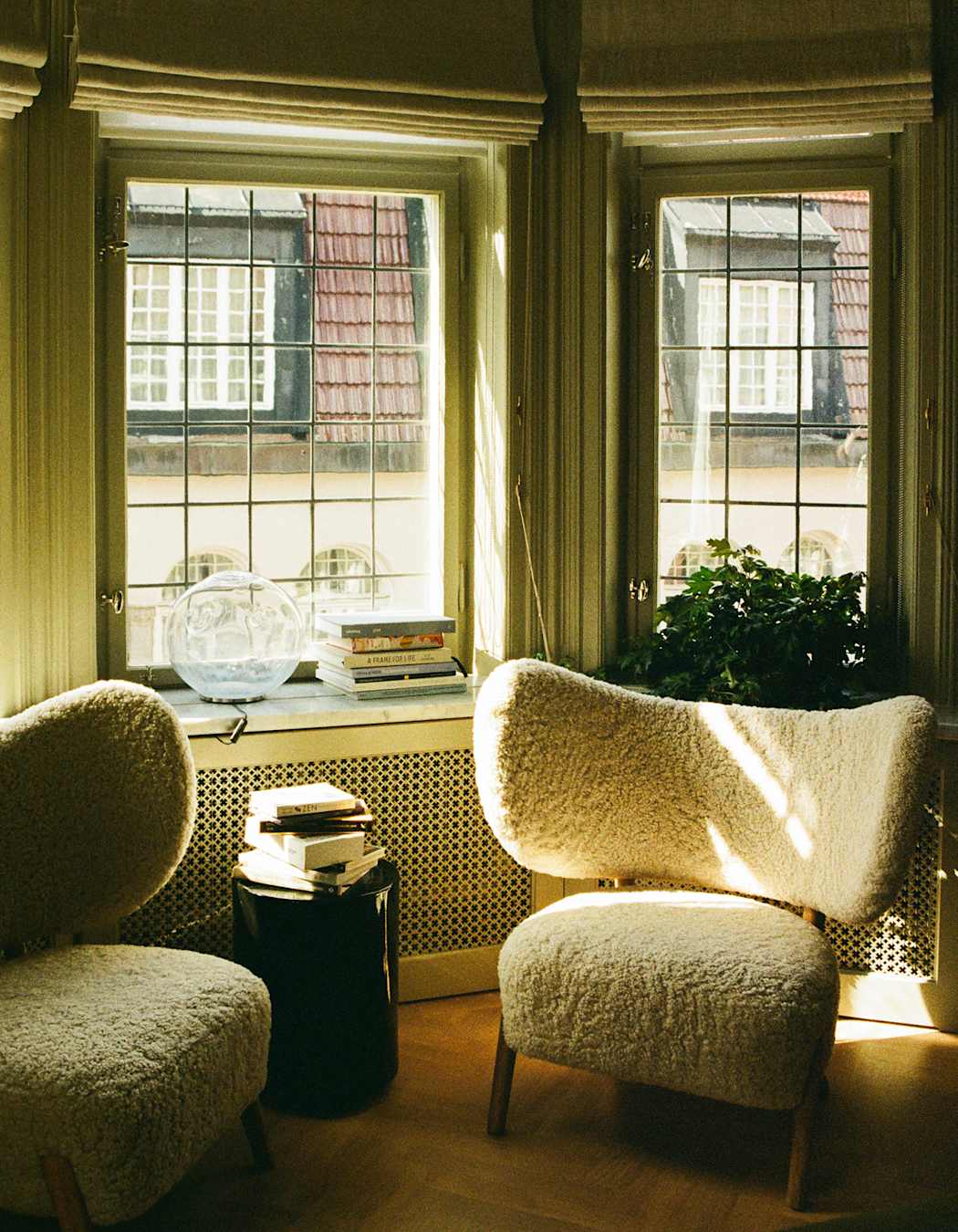 Two fluffy chairs in front of the window, next to a pile of books and Scandinavian decor